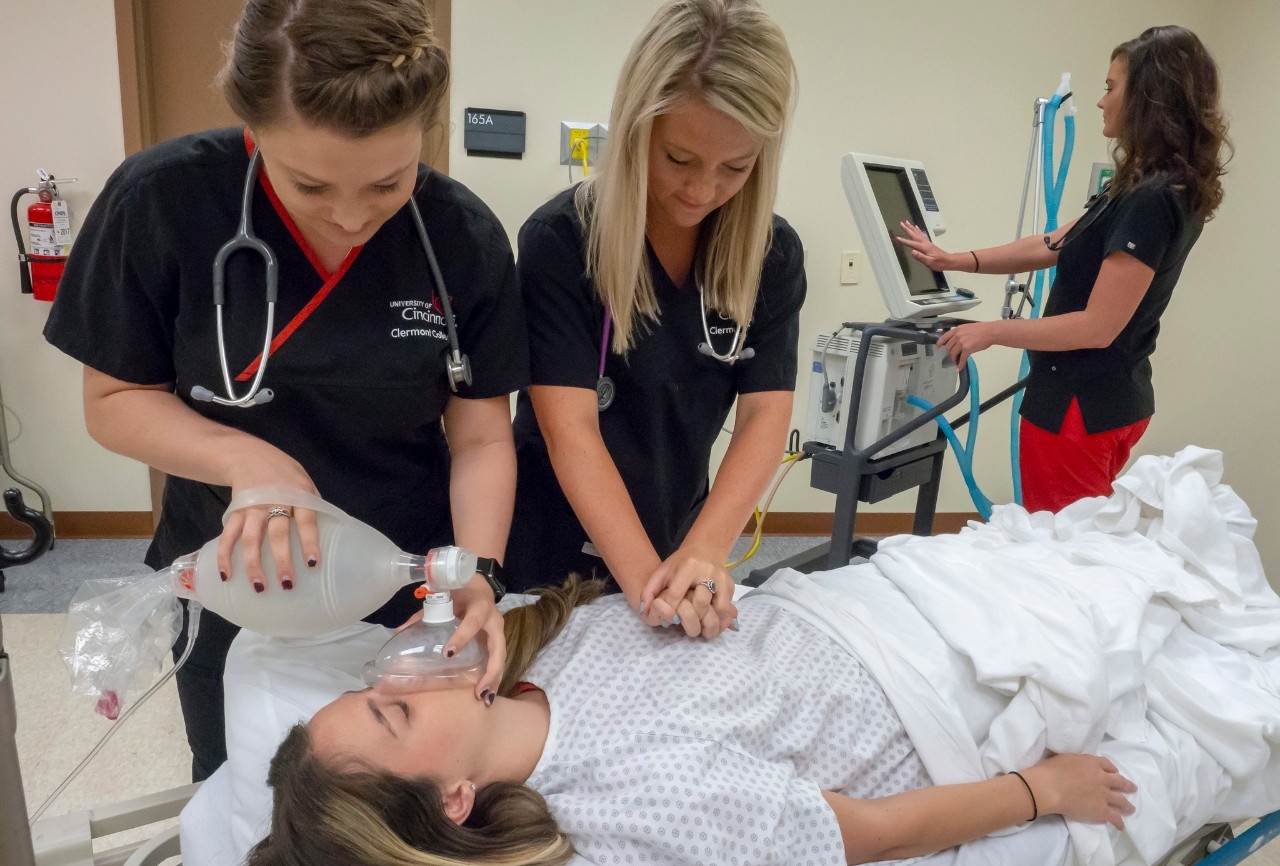 Students in scrubs administering compressions for a photo