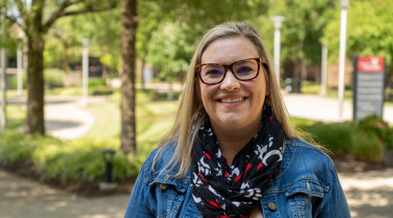 Middle aged woman wearing uc scarf smiles at the Clermont campus