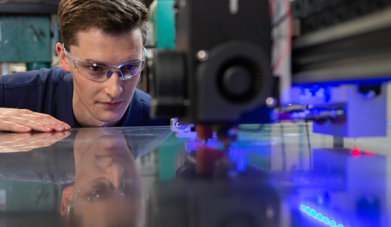 male student watches machine automation